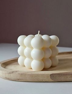 a white candle sitting on top of a wooden tray