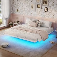 a bed with blue light underneath it in a room next to a window and pictures on the wall