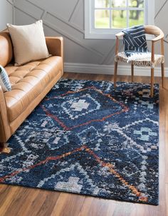 a living room area with a couch, chair and rug in front of a window