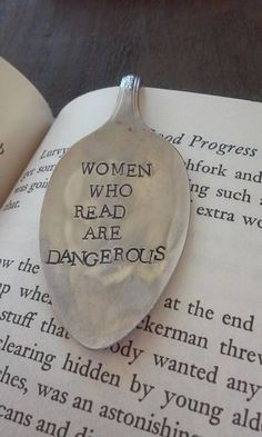 a spoon sitting on top of an open book with words written on it in cursive writing