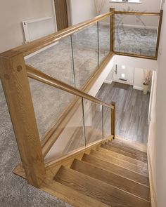 a wooden staircase with glass railing and handrail