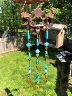 a wind chime hanging from the side of a wooden structure on top of grass