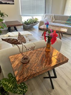 a living room filled with furniture and flowers on top of a wooden table in front of a window