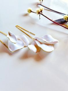 three pairs of white flower earrings sitting on top of a table