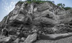 an image of rocks on the beach with sky in backgrounnds and clouds