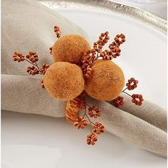 three balls are placed on top of the linen napkins, which have been decorated with orange flowers