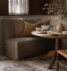 a living room with a couch, table and vase filled with flowers next to a window