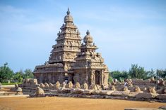 an intricately carved stone structure in the middle of a field with people standing around it