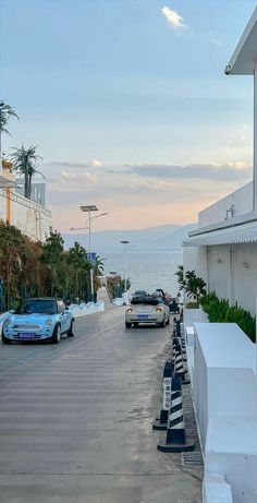 cars are parked on the side of an empty street next to some buildings and palm trees