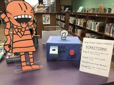 a table with some books on it and a paper cut out of an orange cat