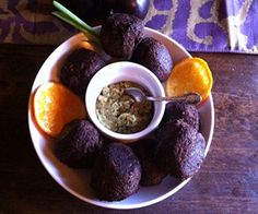 a white plate topped with oranges and chocolate truffles next to a bowl of dip