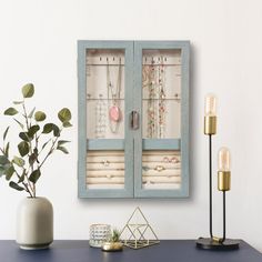 a blue cabinet sitting on top of a table next to a vase with plants in it