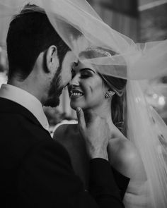 black and white photo of bride and groom with veil over their heads looking into each other's eyes