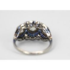 an antique diamond and blue sapphire ring with filigrees in the center, on a white background