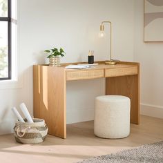 a wooden desk sitting next to a window in a room with a rug on the floor