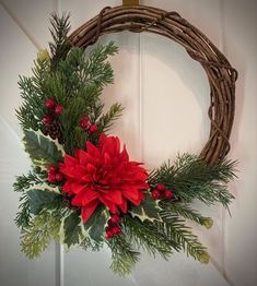 a wreath with poinsettis and greenery hanging on a door