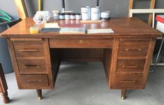 an old wooden desk with lots of paint and other items on it's top