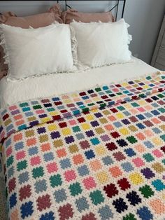 a crocheted blanket on top of a bed next to pillows and pillow cases