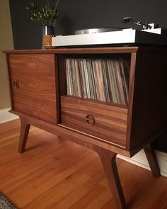 an old record player is sitting on top of a wooden cabinet with vinyl records in it