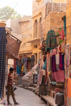 a man is walking through an alley way with many items on display and clothes hanging up to dry