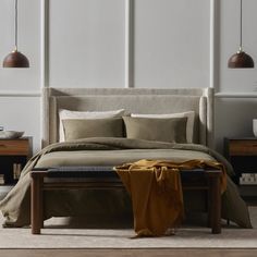 a bed with two lamps hanging above it and a blanket on the bottom of the bed