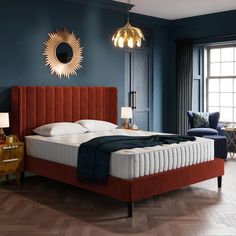 a bedroom with blue walls and wooden flooring has a large bed in the middle