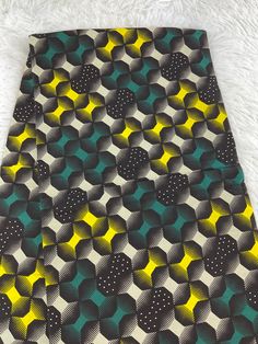 a tie with black, yellow and green designs on it sitting on a white furnishing