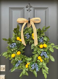 a wreath with lemons, blue berries and green leaves hangs on the front door