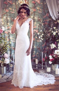 a woman in a wedding dress is talking on her cell phone while standing next to flowers and candles