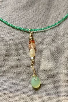 This choker necklace is 14 inches of green quartz, with accents of amethyst, rose quartz, mother of pearl, and chalcedony.  The findings are Sterling silver, and the drop is 2 inches.  The necklace lays high on the neckline, just at the collar bones, but the drop of 2 inches makes this very dramatic.  Shipping in the US is free.  I donate a portion of my proceeds to charity. Handmade Green Spiritual Gemstones, Handmade Chrysoprase Dangle Jewelry, Bohemian Gold Jewelry With Green Onyx, Bohemian Green Onyx Gold Jewelry, Green Handmade Dangle Crystal Necklaces, Handmade Green Crystal Dangle Necklaces, Green Dangle Lariat Necklace As Gift, Handmade Green Dangle Crystal Necklace, Green Dangle Lariat Necklace For Gift