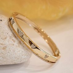 There are so many ways to love this fresh and fun cubic zirconia bangle bracelet. This darling bangle features heart designs made with CZ stones which adorns a band on one side. A meaningful look for the one you adore. - Stones Material: Cubic Zirconia. - Stones Shape: Round. - Metal: Brass. - Plating: 18k Gold plated. - Interior Diameter: 60 mm. - Width: Aprox. 5 mm. - Clasp: Snap Closure. - Circumference Inches: 7.42 Ships in a Balara Gift Pouch. Available in Gold. SKU# B1683 Gold Kada Design For Women Stylish, Gold Band Bracelet For Women, Indian Gold Bracelet For Women, Ladies Bangle Design, Bracelet Bangles For Women, Unique Gold Bangles For Women, Gold Kada Design For Women Indian, Bangle Gold Designs, Cubic Zirconia Bangle For Valentine's Day