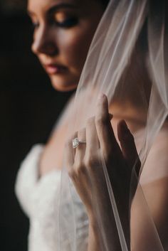 a woman in a wedding dress is holding her veil