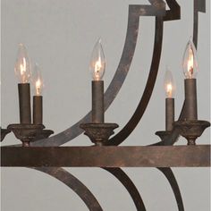 a chandelier with five lit candles hanging from it's arms and an iron frame