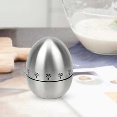 an egg shaped thermometer sitting on top of a counter next to a bowl