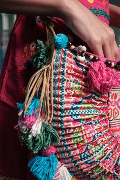 a close up of a person holding a colorful bag with tassels on it