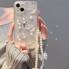 a woman is holding up her phone case with pearls and bows on the cover,