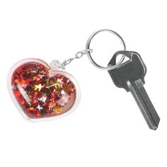 a heart shaped keychain with red and yellow glitters on it's side