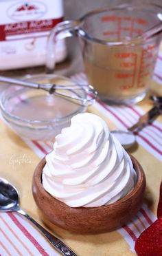 whipped cream in a wooden bowl on a table with spoons and other food items