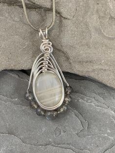 The tranquil beauty of this white moonstone and Labradorite  necklace is stunning. Moonstone has a soothing nurturing energy paired with Labradorite which holds the power of positivity, and it will negate all the negative energies around you.  The delicate glow of the moonstone is beautiful in its simplicity. I chose to enhance this beautiful stone with 7 genuine labradorite gemstones for added sparkle. Set in a Celtic inspired silver wire design to let the natural beauty of the gemstones shine. White Moonstone Moon Phase Necklace, White Moonstone Crystal Necklace With Moon Charm, White Moon Shaped Spiritual Necklaces, White Moon Phase Jewelry For Meditation, White Moon Shaped Spiritual Necklace, Handmade White Moon-shaped Necklace, Spiritual White Moon Necklaces, Handmade White Moon Shaped Necklace, Spiritual White Moon Necklace