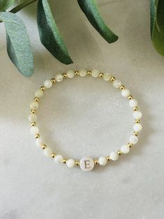 - Beautiful dainty pearl initial bracelet that makes a gorgeous bracelet gift. Soft and delicate with tiny 18 gold filled beads and freshwater shell initial bead. Coordinating pieces in shop. Beaded on high quality stretch cord and secured. - 3mm 18k gold filled beads   4mm mother of pearl beads    8mm freshwater shell initial bead. - Purchase is sent in a white velvet drawstring jewelry bag, making the perfect bracelet gift for bridesmaid, bracelet for mom, anyone special or just yourself. - To care for your bracelet, please roll on and off wrist. Repeated stretching can wear the elastic over time. Avoid excessive contact with water and chemicals. - We highly recommend measuring your wrist before ordering. Please see our sizing guide in the listing photos.  - We strive to get orders out a Couple Beaded Bracelets Pearl, Beaded Initial Bracelet, Initial Bead Bracelet, Gold Pearl Beaded Bracelets With Letter Beads, White Dainty Beaded Bracelets For Bridesmaid Gift, Elegant Pearl Bracelet With Letter Beads As Gift, Elegant Pearl Bracelet With Letter Beads For Gift, Dainty White Beaded Bracelets For Bridesmaids, Delicate Beaded Bracelets With Pearl Charm For Bridesmaids