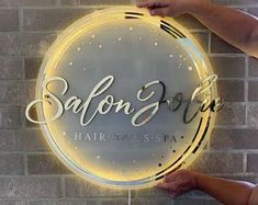 someone holding up a neon sign that says salon spa