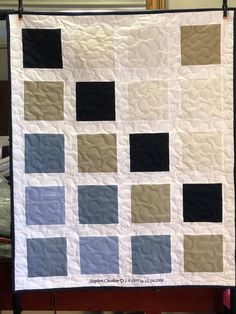 a white and blue quilt hanging on a wall