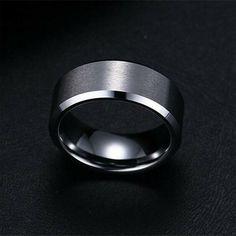 a black and silver wedding ring on a black surface with the light shining through it