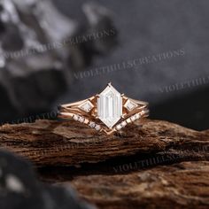 a diamond ring sitting on top of a piece of wood in front of some rocks