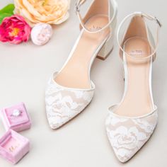 two pairs of white shoes sitting next to a pink box with flowers on the side