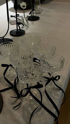 a table topped with lots of clear glasses on top of a white cloth covered table