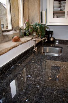 a kitchen with granite counter tops and stainless steel sink faucet next to window