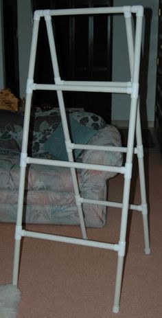 a white metal step stool sitting on top of a carpeted floor next to a couch