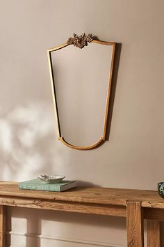 a wooden table with a book on top of it next to a wall mounted mirror