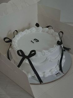 a white cake in a box with black ribbon